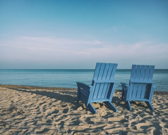 two blue beach chairs near body of water