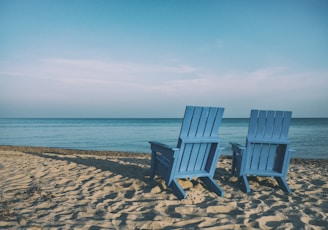 two blue beach chairs near body of water