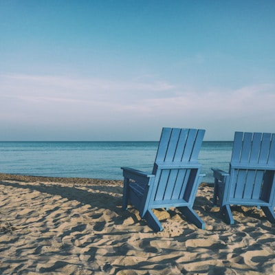 two blue beach chairs near body of water