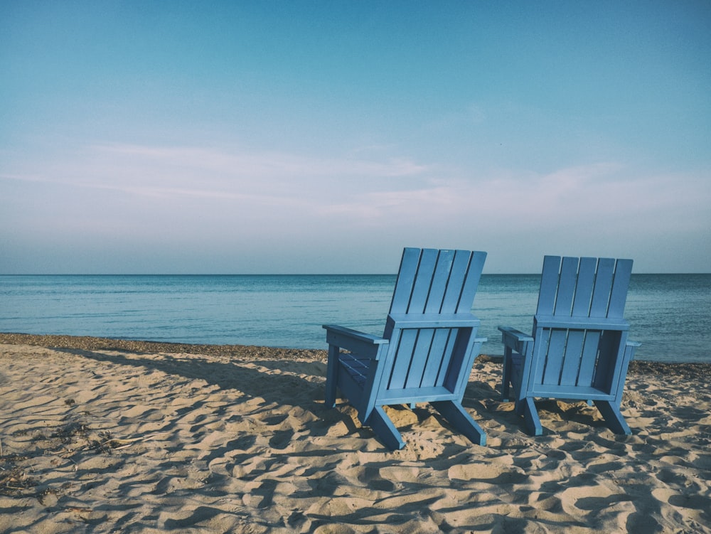 duas cadeiras de praia azuis perto do corpo de água