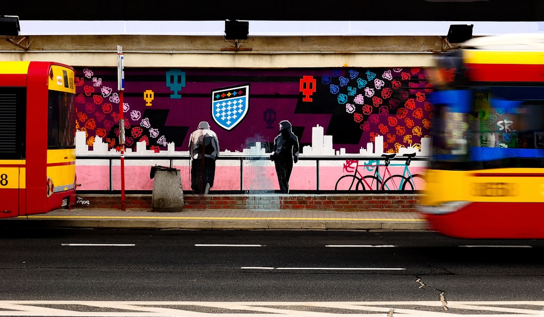 two person standing while waiting on bus stop, Bus in front of street art