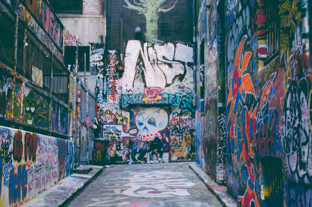 Colorful grunge graffiti artwork covering walls in alleyway with skull in Hosier Lane