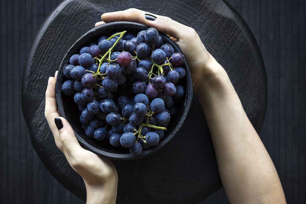 person holding bowl of grapes