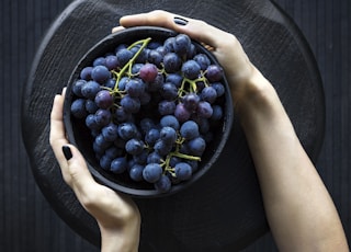 person holding bowl of grapes