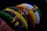 A series of colorful beaded bracelets arranged side by side, showcasing intricate patterns and a variety of vibrant colors including green, red, yellow, white, and blue. The beads are small and densely packed, creating textured and detailed designs.
