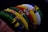 A series of colorful beaded bracelets arranged side by side, showcasing intricate patterns and a variety of vibrant colors including green, red, yellow, white, and blue. The beads are small and densely packed, creating textured and detailed designs.
