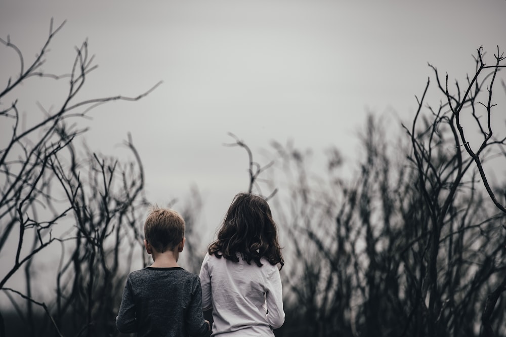 niño y niña rodeados de árboles