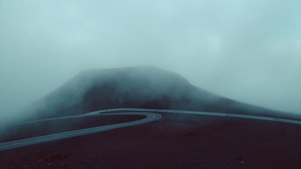 concrete road near mountain during foggy weather