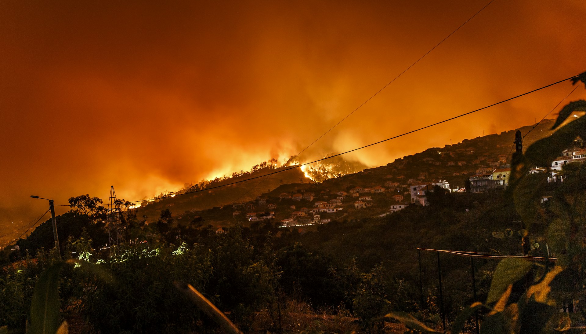 Forest fire raging through a hillside village