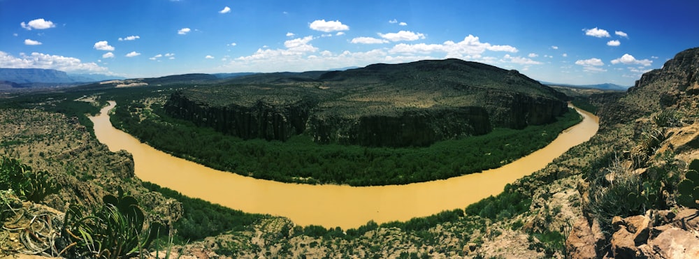 fotografia aérea do rio ao lado da montanha verde durante o dia
