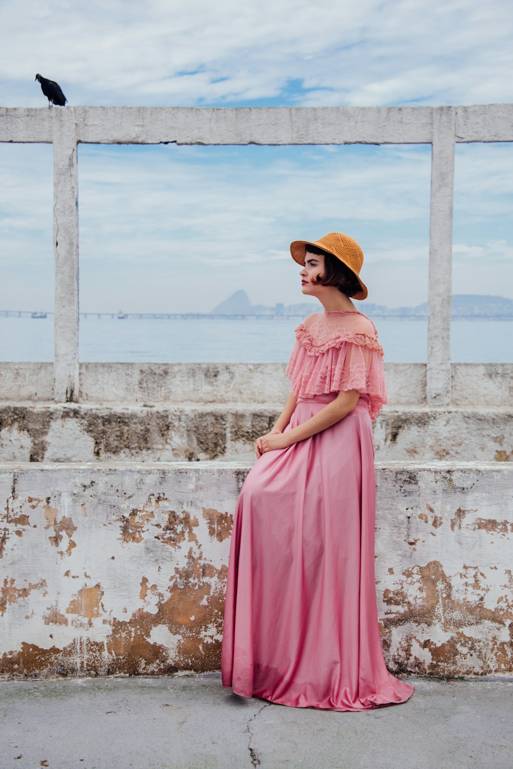 mujer con vestido rosa de pie junto a la pared blanca