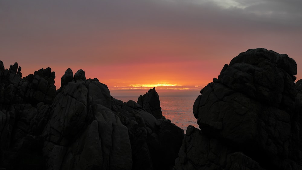 brown cliff near body of water at sunset