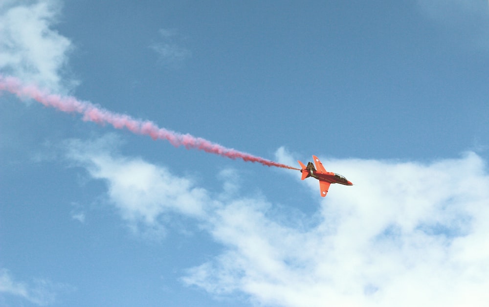Foto di aereo a reazione con fumo rosso che vola in aria
