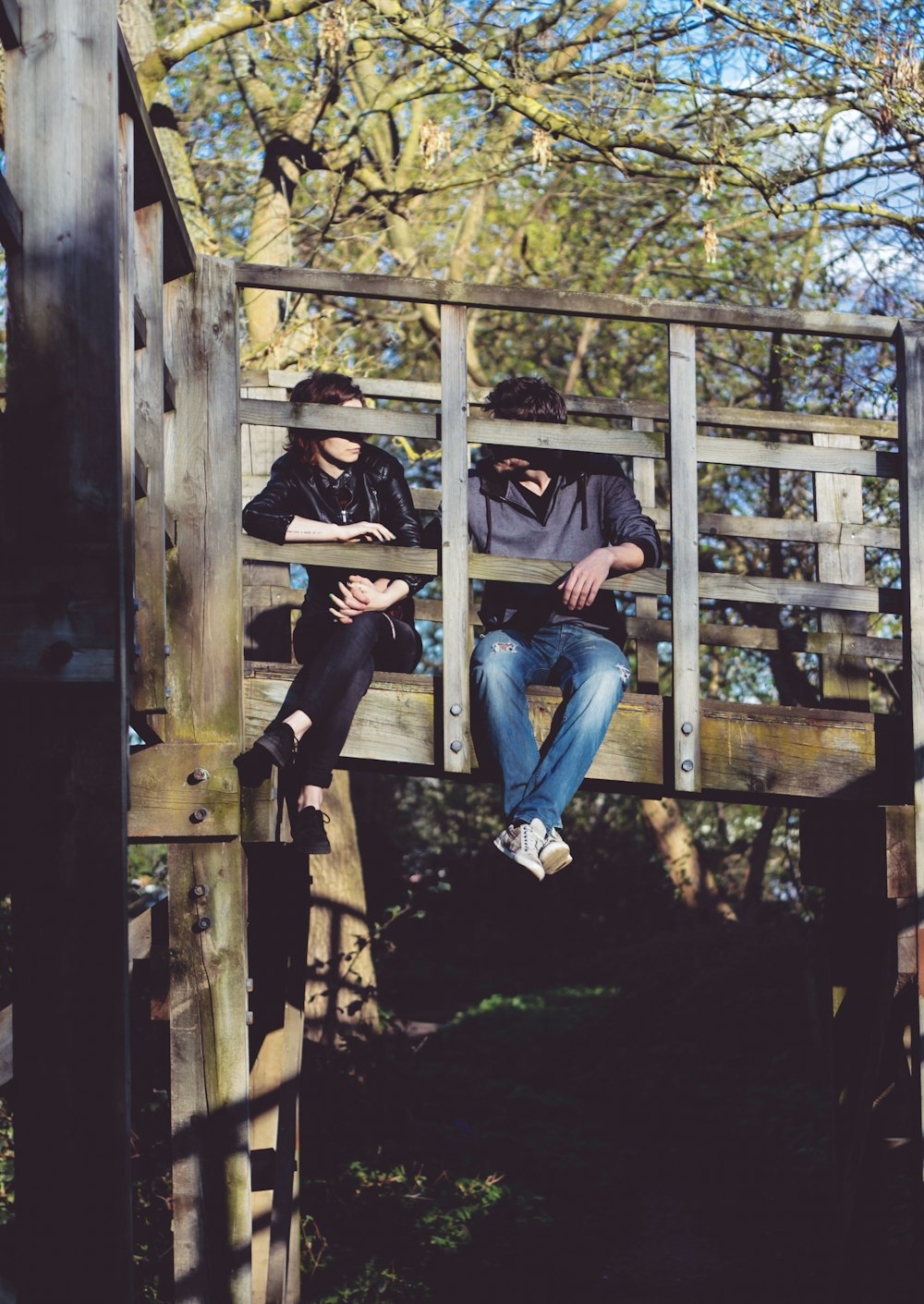 Mann und Frau sitzen auf der Seite der Holzbrücke