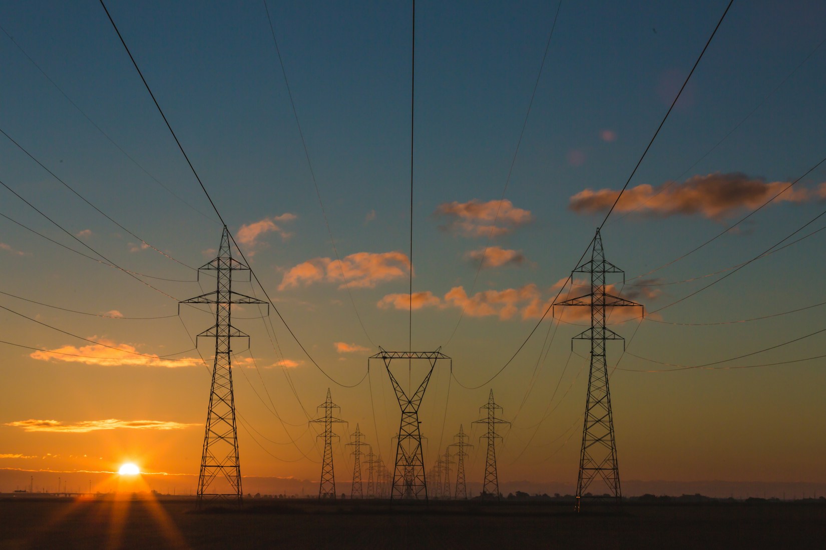 Transmission lines against a dusk sky over an industrial corridor
