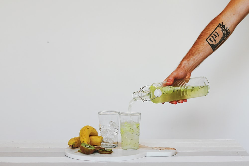 person pouring juice on glasses on table