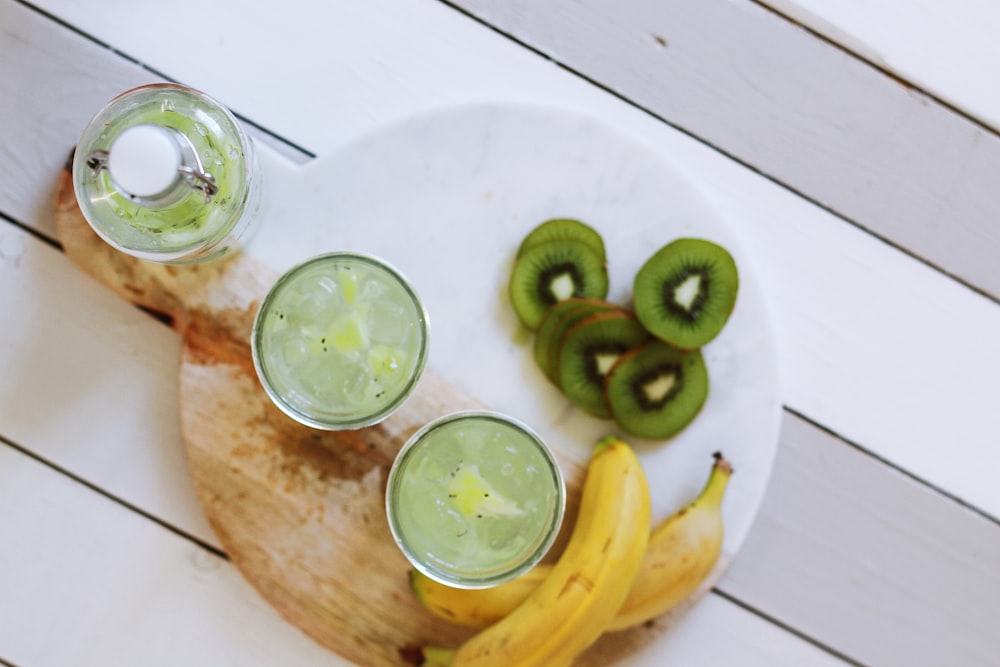 The top view of a bottle, two glass cups and fruits on a plate in London