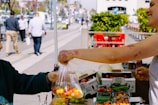 Reusable shopping bags filled with fresh vegetables at a market.