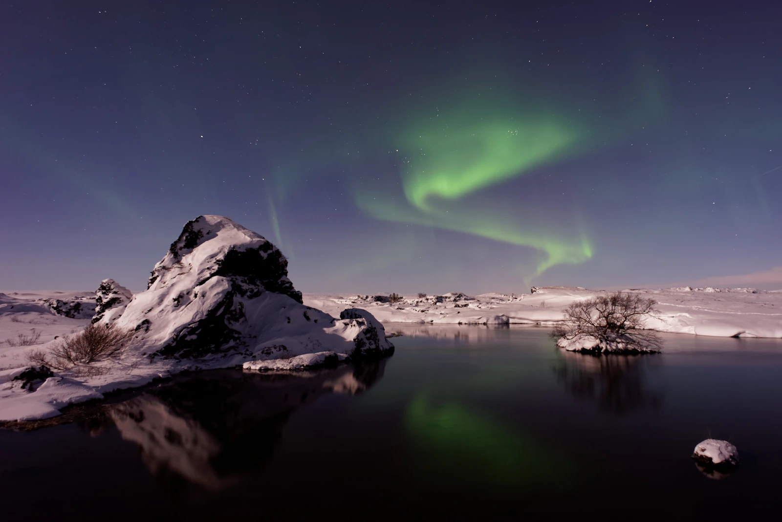 The aurora over Lake Mývatn and its lava formations — Iceland