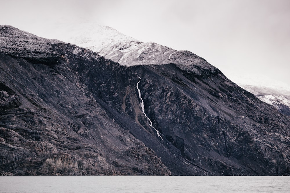 grayscale photo of body of water surrounded by mountain