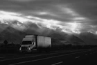 A convoy of Magno Transporte trucks moving along a highway under a dramatic sky.