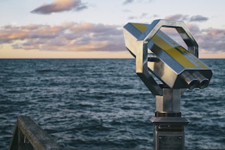 gray metal telescope near body of water