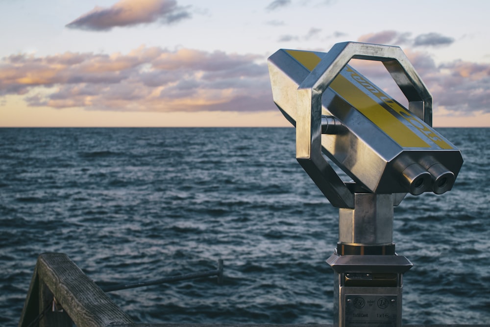 Telescopio de metal gris cerca de un cuerpo de agua