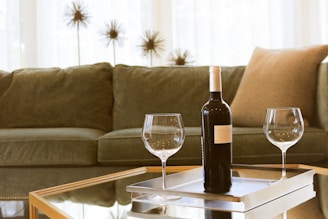 black wine bottle beside two wine glasses