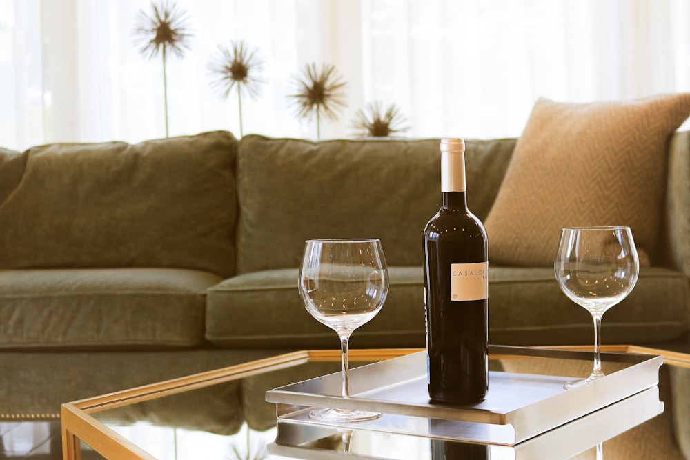 black wine bottle beside two wine glasses