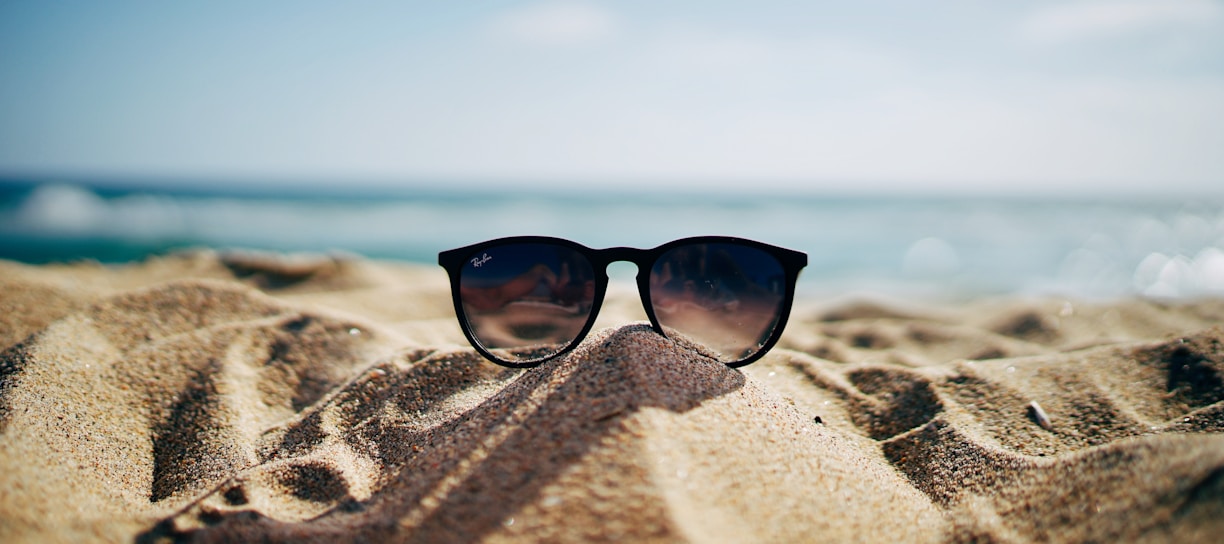 black Ray-Ban Wayfarer sunglasses on beach sand