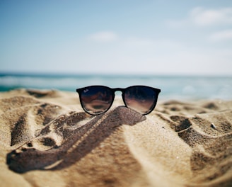 black Ray-Ban Wayfarer sunglasses on beach sand