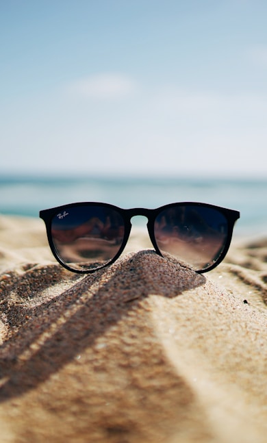 black Ray-Ban Wayfarer sunglasses on beach sand