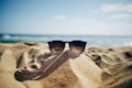black Ray-Ban Wayfarer sunglasses on beach sand