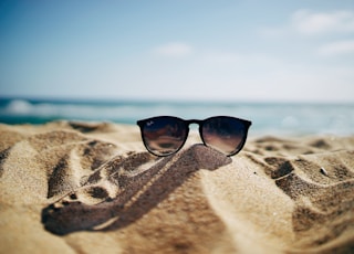 black Ray-Ban Wayfarer sunglasses on beach sand