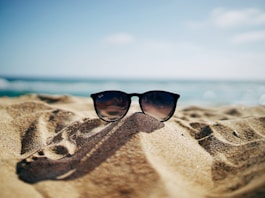 black Ray-Ban Wayfarer sunglasses on beach sand