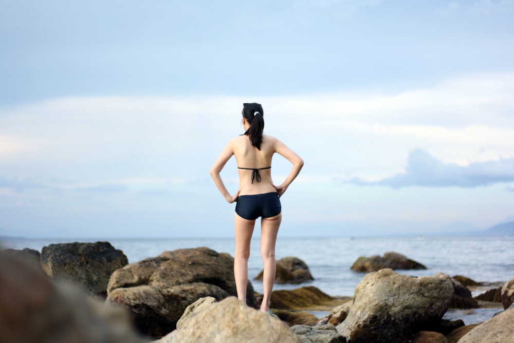 woman standing on stones near body of water