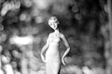 A porcelain figurine of a woman in an elegant dress stands out against a background of soft-focus bokeh circles that create a dreamy and abstract effect.