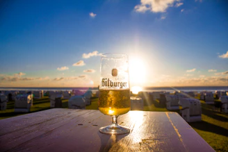 A cold beer sitting on a wooden porch railing overlooking a flawless backyard.