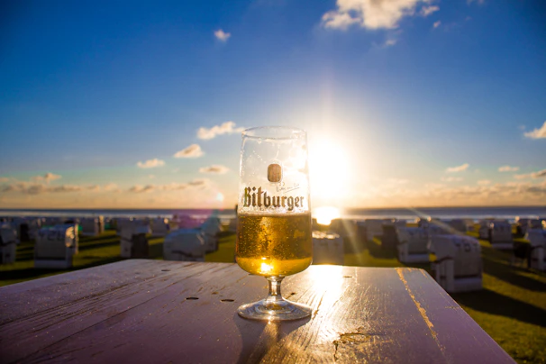 A cold beer sitting on a wooden porch railing overlooking a flawless backyard.