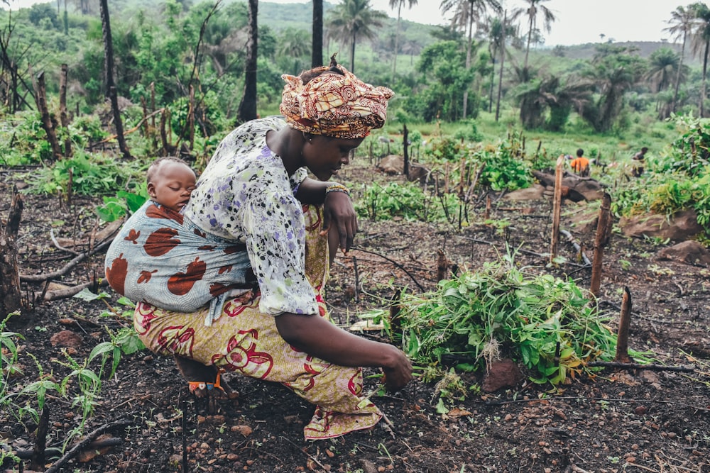 women carrying baby in her back close-up photography