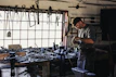 Artisan crafting a luxury fence piece in a workshop filled with tools