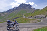 A winding mountain road with a motorcycle parked at a scenic overlook.