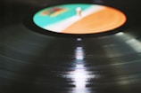 Close-up of a vinyl record spinning with blue and orange reflections on its surface.