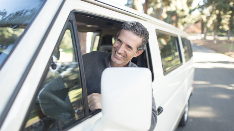 man in gray sweater leaning on van window