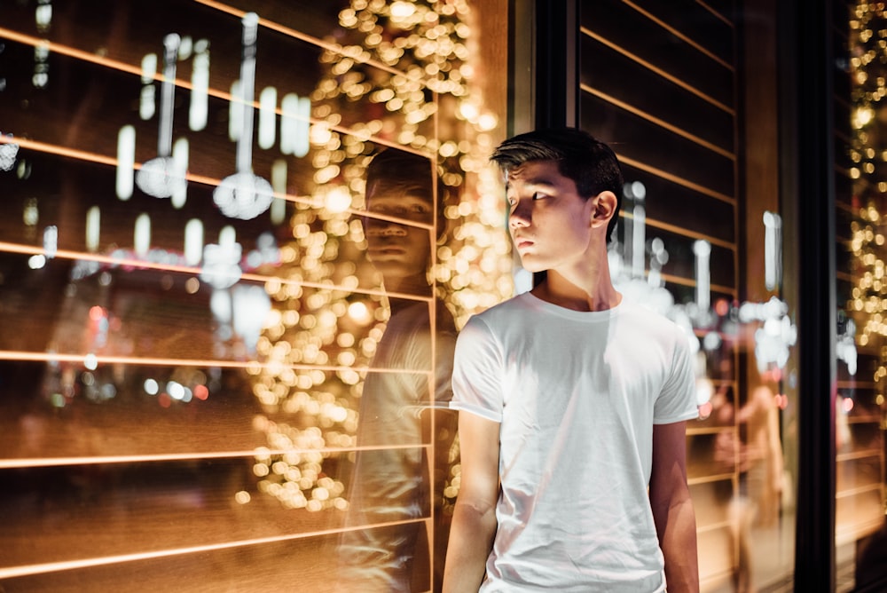 a young man standing in front of a window