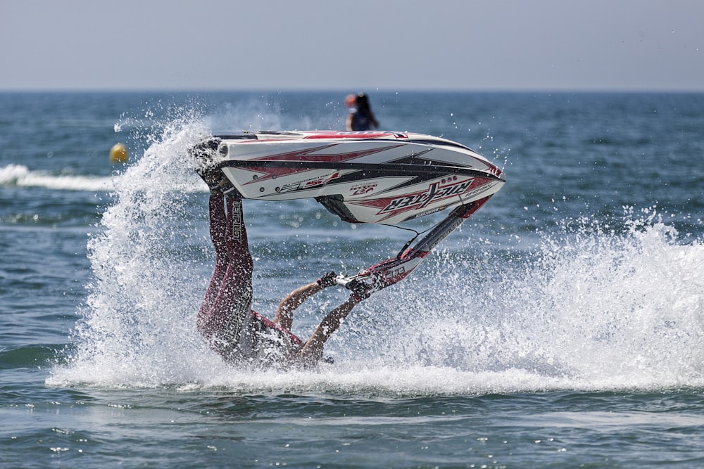 person riding personal watercraft doing acrobat on body of water during daytime