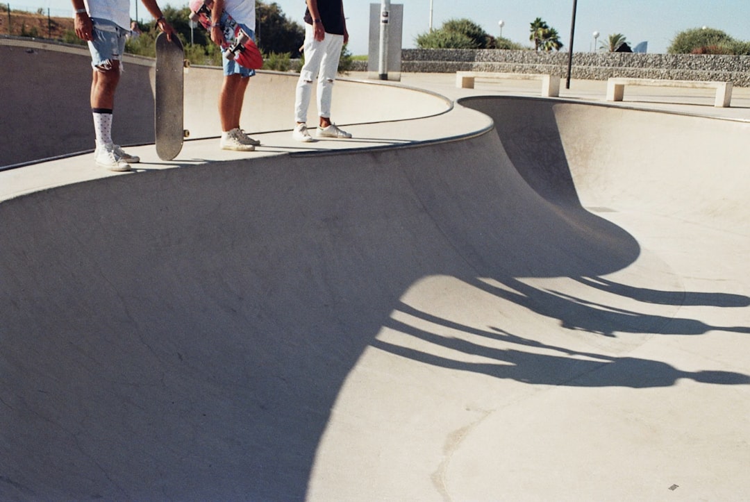 three skaters standing on skateboard concrete ramp with shadow at daytime