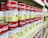 A supermarket shelf filled with rows of Campbell's canned soups, specifically labeled as 'Ayam & Cendawan Creamy Chicken Mushroom.' The cans feature a vibrant red and white label with images of creamy soup and green herbs. The shelf is well-organized, showing multiple stacks of identical cans, creating a sense of abundance and variety.