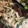 A selection of fresh produce including ginger, lemongrass bundles, banana flowers, and leafy greens neatly arranged in crates at a market.
