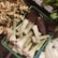 A selection of fresh produce including ginger, lemongrass bundles, banana flowers, and leafy greens neatly arranged in crates at a market.